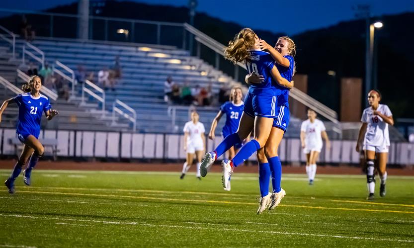 Two soccer players celebrate a goal